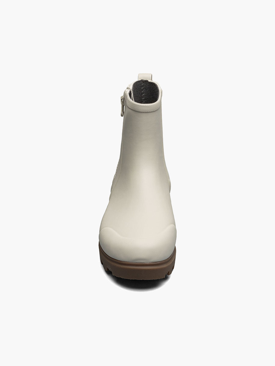 Vue de face d'une bottine blanche à la finition lisse, dotée d'un talon légèrement surélevé et d'une semelle marron. Cette bottine présente un design élégant, une fermeture éclair sur le côté et un bout arrondi.