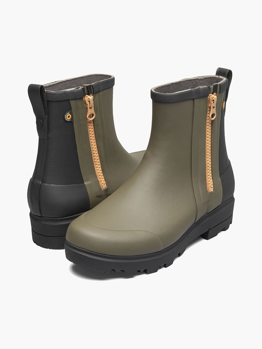 Une paire de bottines vertes avec des fermetures éclair beiges de chaque côté. Elles sont dotées d'une semelle noire robuste et d'une languette à l'arrière pour un enfilage facile. Un petit logo circulaire orne les côtés extérieurs.