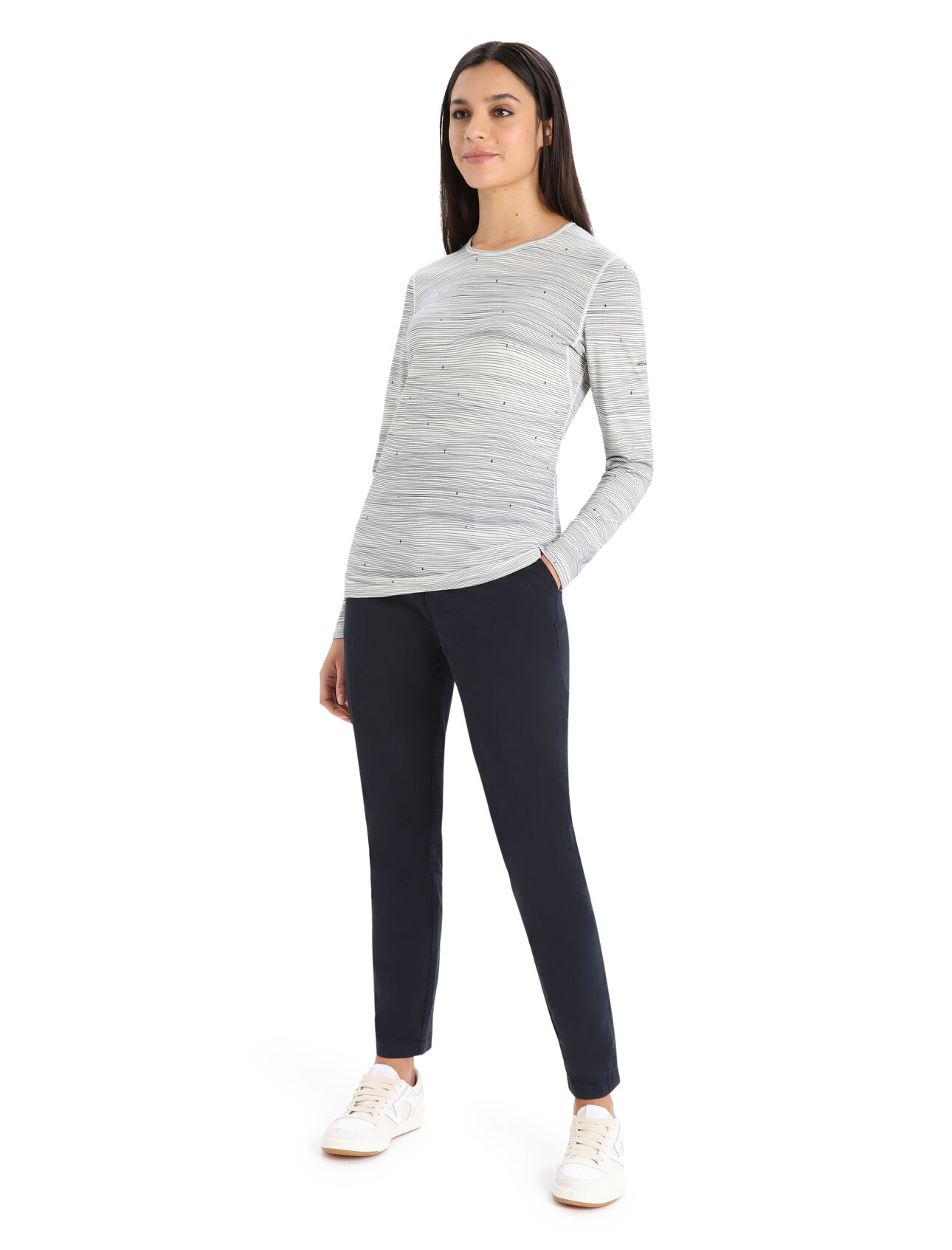 HAUT COUCHE DE BASE À MANCHE LONGUE 200 OASIS LONG SLEEVE CREWE EN MÉRINOS POUR FEMME de couleur Snow/Midnight navy porter par une femme vu de la tête au pied de face la main gauche dans ca poche de son pantalon