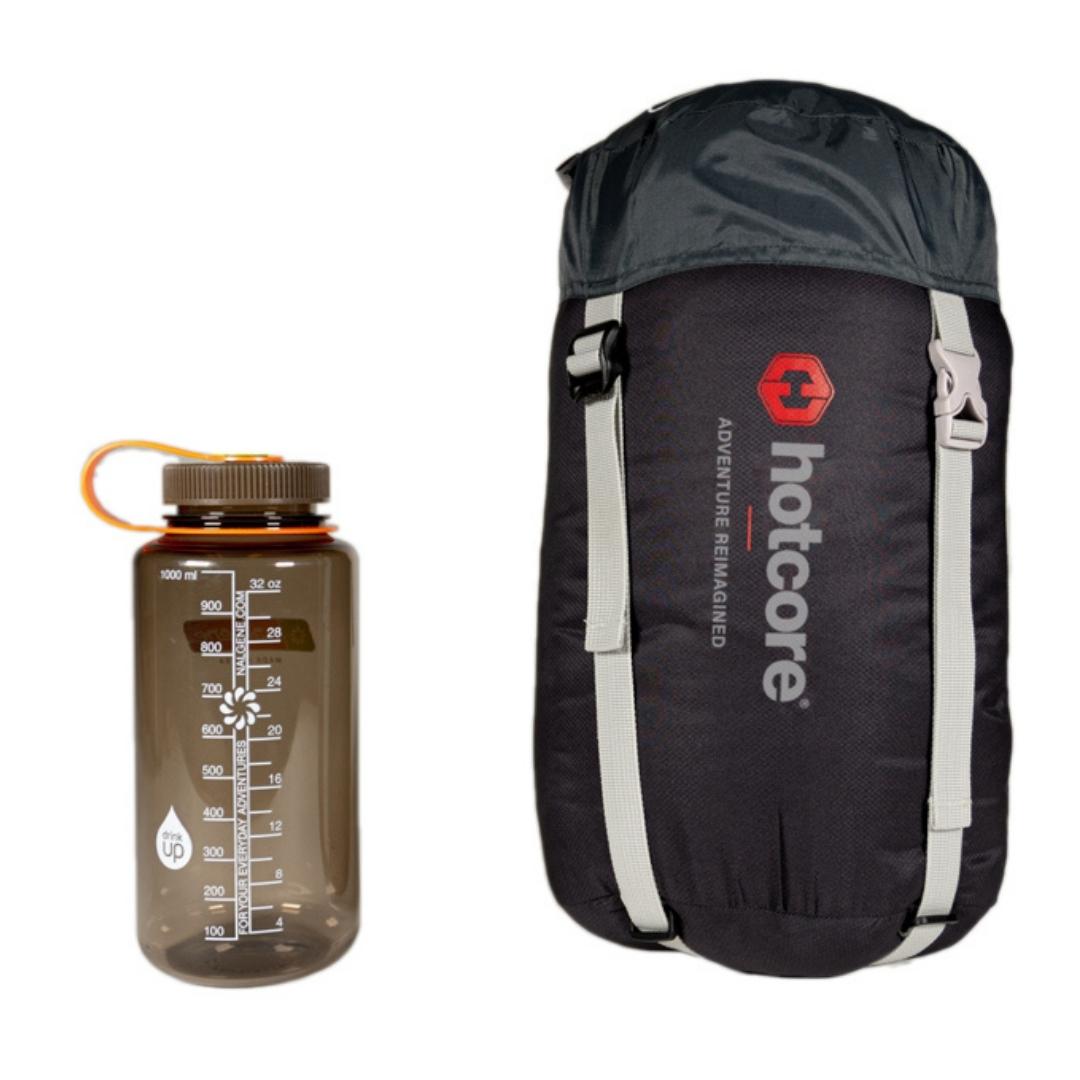 sac de couchage hotcore t200 vue du sac de couchage dans son sac de transport comparé a une boutielle d'eau