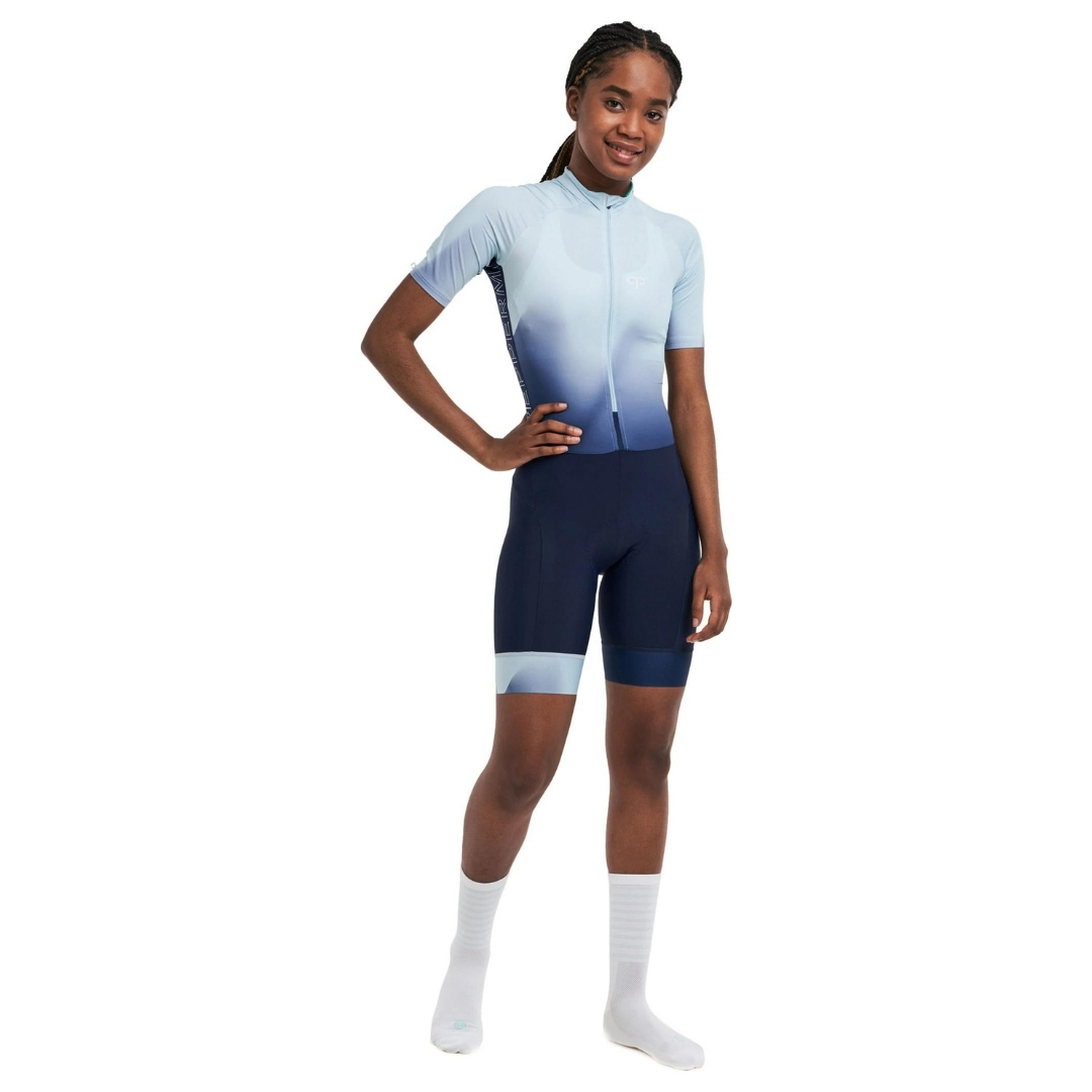 COMBINAISON DE VÉLO PEPPERMINT SIGNATURE À MANCHES COURTES POUR FEMME COULEUR COURAGE-LIGHT BLUE PORTÉ PAR UNE FEMME VUE DU BAS DE LA COMBIANAISON