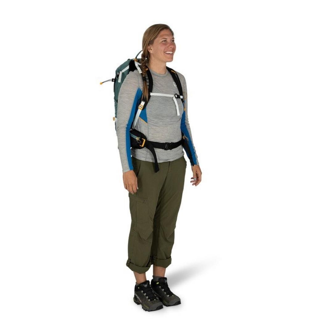 SAC À DOS OSPREY SIRRUS 24 POUR FEMME PORTÉ PAR UNE FEMME VUE DE FACE AVEC LES SANGLES DU SAC ATTACHÉES