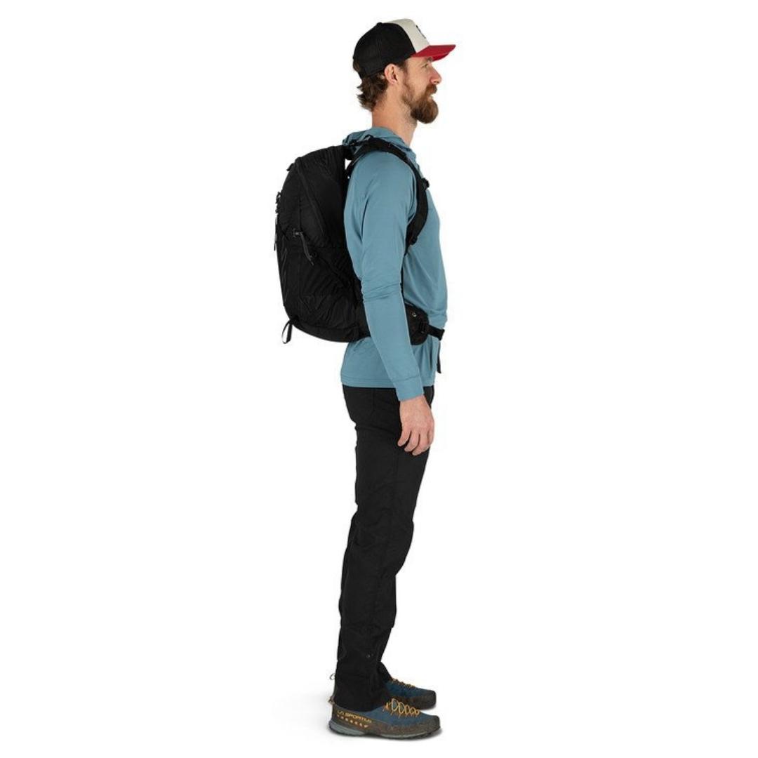 SAC À DOS OSPREY TALON 22 PORTÉ PAR UN HOMME VU DE PROFIL AVEC LE SAC CHARGÉ AU DOS