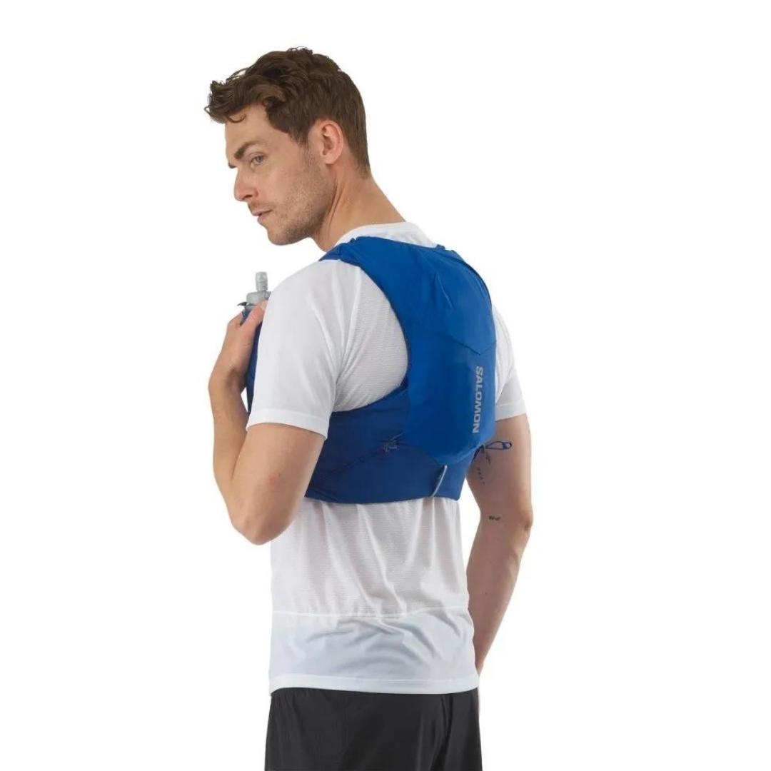 VESTE D'HYDRATATION SALOMON ADV SKIN 5 AVEC BOUTEILLES POUR HOMME couleur NAUTICAL BLUE / EBONY / WHITE vu de dos/profil il tien une bouteille dans la poche avant pour boire