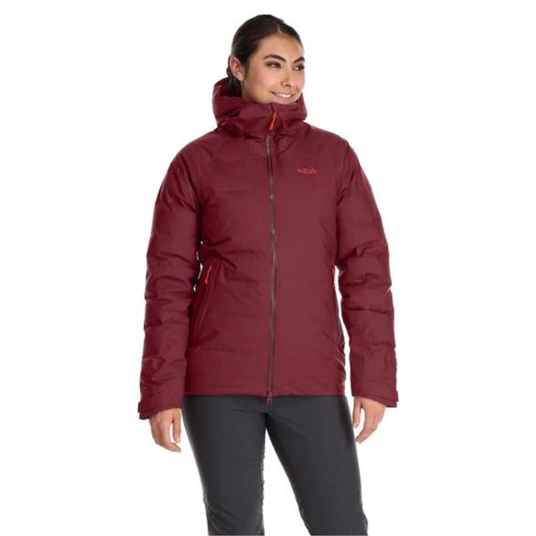 MANTEAU ISOLÉ EN DUVET RAB VALIANCE POUR FEMME couleur Deep Heather vu du manteau rouge brique avec détails orangés porté par une femme vue de face