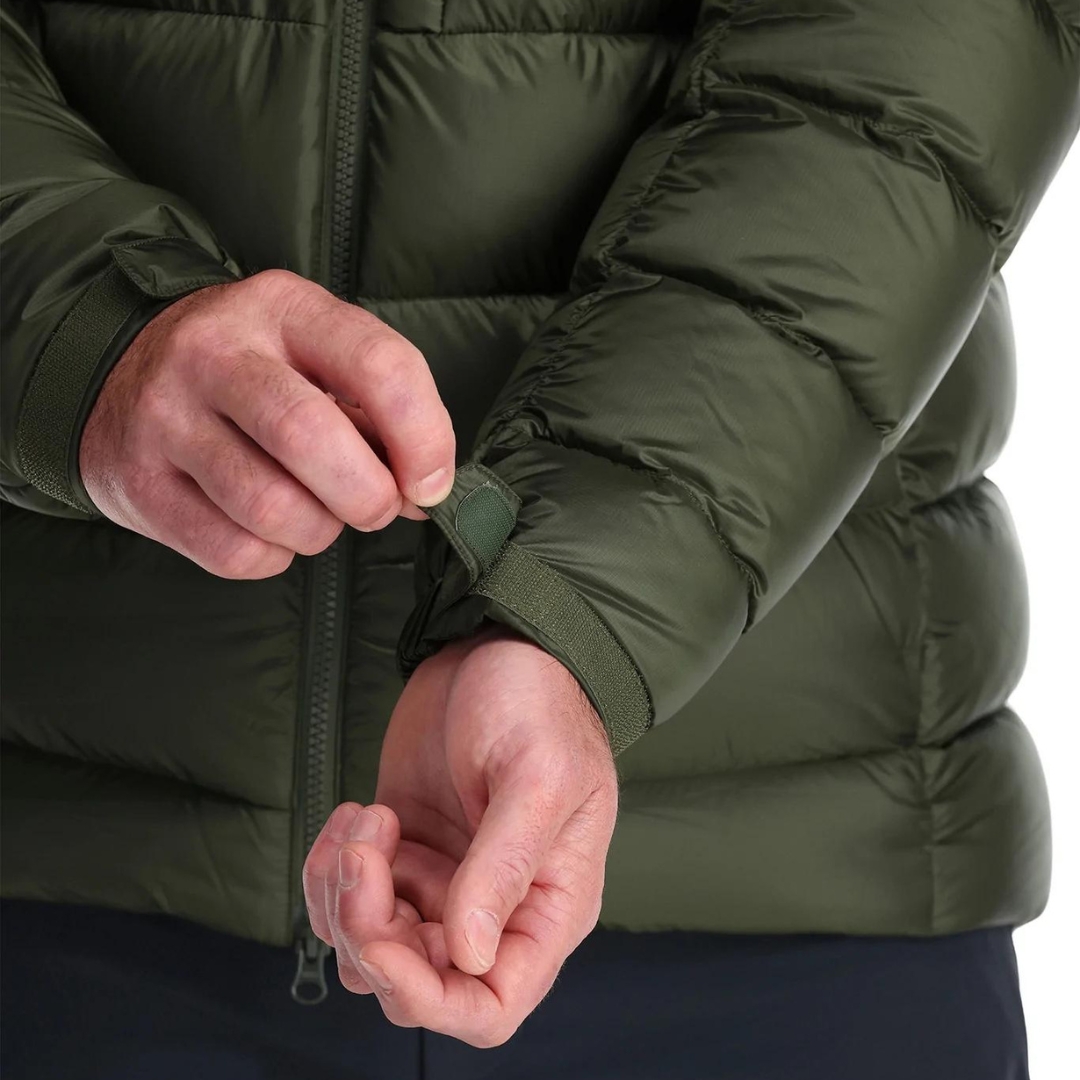 MANTEAU ISOLÉ EN DUVET RAB AXION PRO POUR homme couleur army porté par un homme qui ajuste la bande velcro au tour du poignet du manteau vert armé