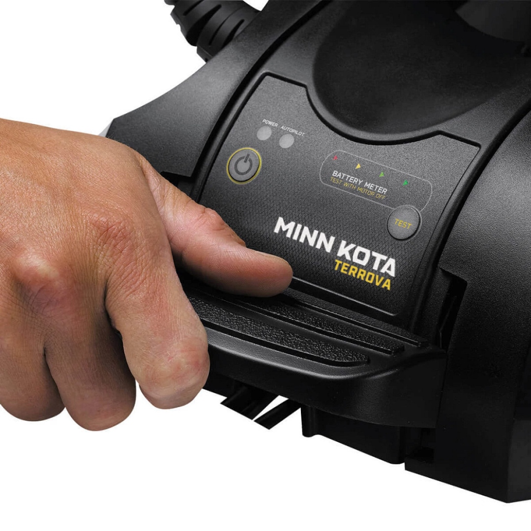 MOTEUR ÉLECTRIQUE POUR BATEAU MINN KOTA TERROVA 55/IP BT NO FOOT PEDAL vue d'un homme utilisant le levier de rangement on voit le nom Minn Kota en blanc sur le moteur noir