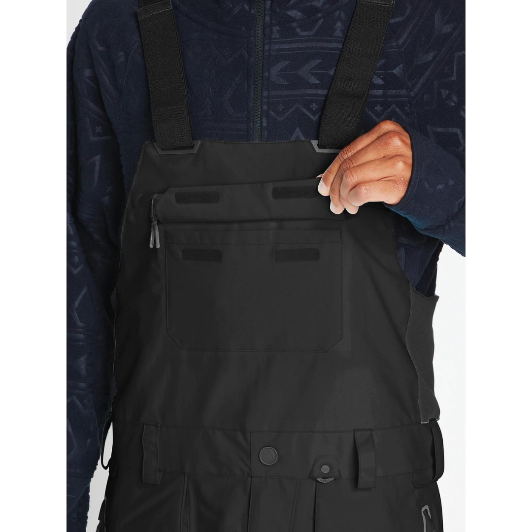 SALOPETTE ISOLÉE VOLCOM RAIN GORE-TEX POUR HOMME couleur black portée par un homme qui montre la poche à rabat à la poitrine se fermant avec velcro