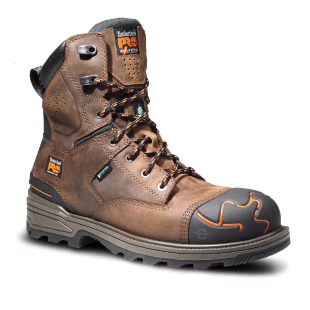 Une botte de travail Timberland PRO marron robuste avec des accents noirs, des coutures orange et un bout renforcé. La botte est dotée d'une semelle robuste, d'œillets métalliques et d'un col de cheville rembourré, conçus pour la durabilité et le confort.