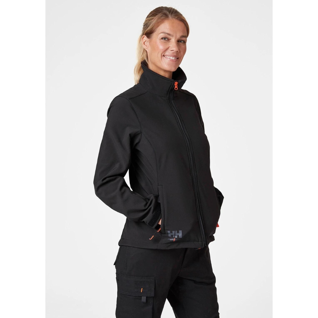 MANTEAU DE TRAVAIL HELLY HENSEN LUNA SOFTSHELL POUR FEMME porté par une femme vue de face avec les mains dans les poches latérales du manteau noir