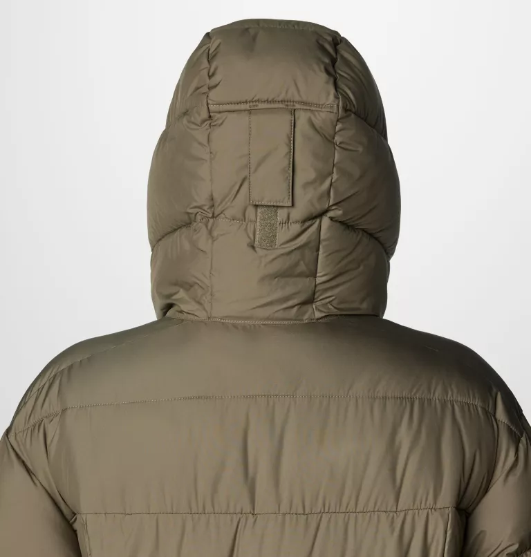 Vue arrière d'une personne portant une doudoune à capuche vert olive. La capuche est relevée, révélant un motif rectangulaire cousu dans le dos. La veste semble épaisse et isolante, adaptée au temps froid.