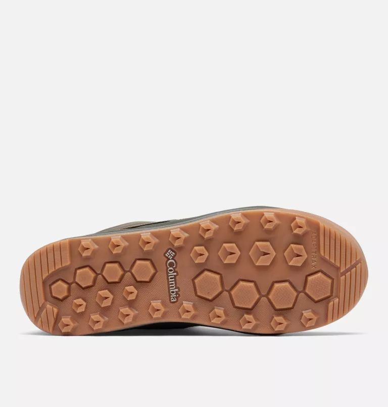 L'image montre la semelle d'une chaussure avec un motif hexagonal texturé. La semelle est marron clair avec le mot « Columbia » imprimé près du centre. Le fond est blanc uni.