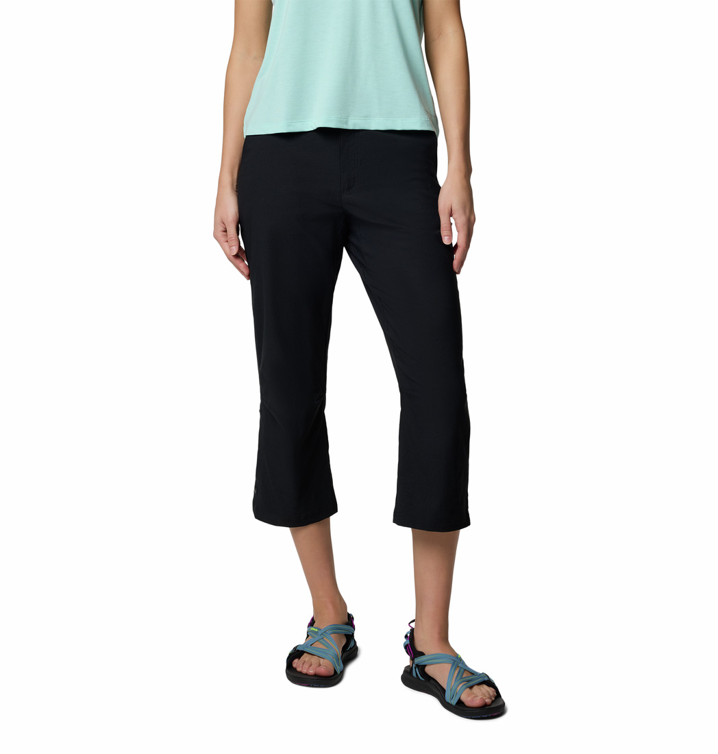Une personne portant un haut à manches courtes bleu clair, un pantalon capri noir et des sandales bleu sarcelle et noires, représentée des épaules vers le bas sur un fond blanc.
