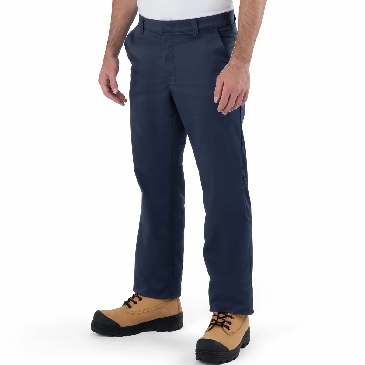 Une personne se tient debout devant un fond blanc uni, vêtue d'un PANTALON FLEX TAILLE BASSE bleu marine, d'une chemise blanche et de bottes de travail beiges. Sa tête n'apparaît pas sur la photo.