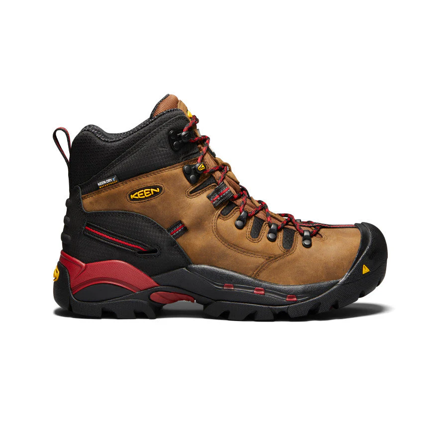 Une botte de randonnée marron et noire avec des accents rouges, une semelle robuste noire, des lacets rouges et le logo KEEN jaune sur le côté, présentée du profil gauche sur un fond blanc.