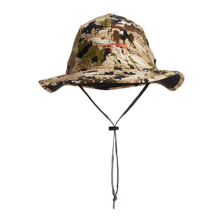 Casquette à large bord avec motif camouflage numérique dans les tons vert, marron et beige, avec une mentonnière réglable et un logo orange sur le devant.