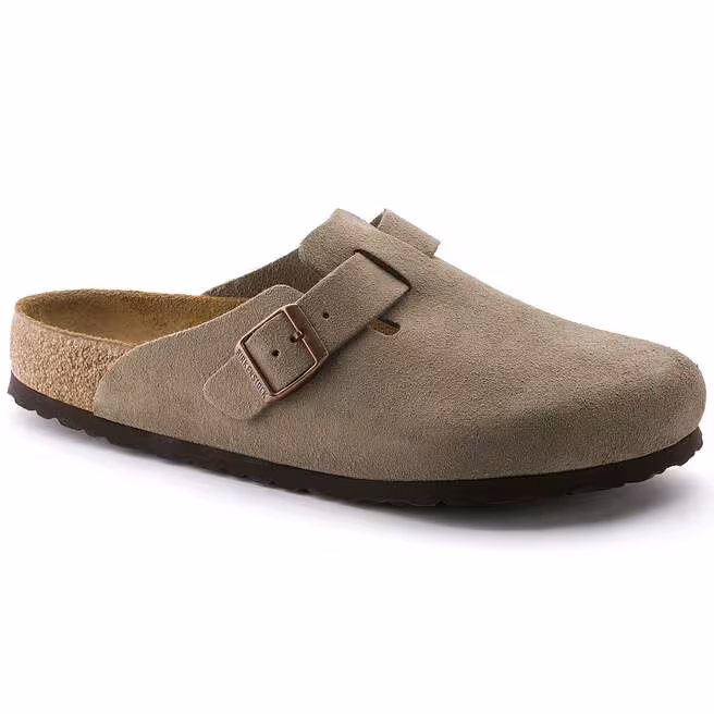 Le BOSTON SOFT FOOTBED SUEDE N est un sabot à enfiler en daim taupe doté d'une assise plantaire en liège, d'une semelle noire et d'une bride à boucle métallique réglable sur le dessus.