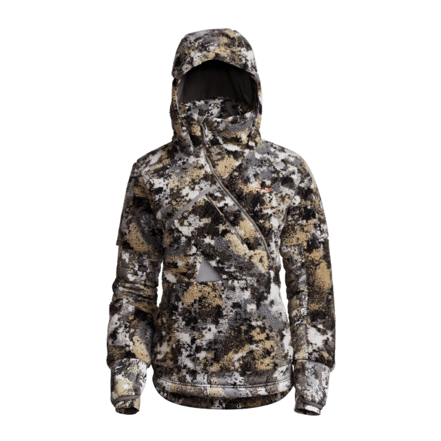 Le MANTEAU DE CHASSE SITKA FANATIC POUR FEMME est présenté sur fond blanc, avec un motif camouflage dans les tons beige, noir, blanc et gris. Cette veste à capuche est dotée d'une fermeture éclair sur le devant et d'une poche poitrine asymétrique.
