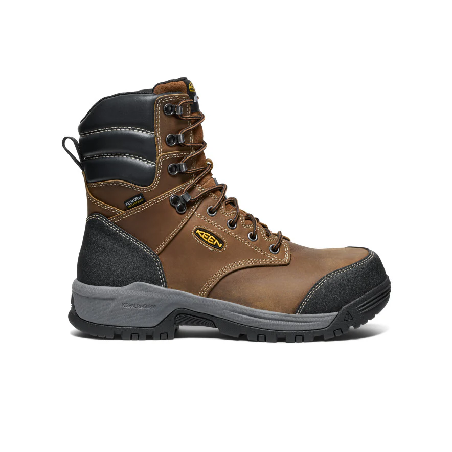 Une botte de travail montante marron et noire avec œillets métalliques, lacets robustes, bout renforcé, cheville rembourrée et semelle grise robuste, présentée de profil sur fond blanc.