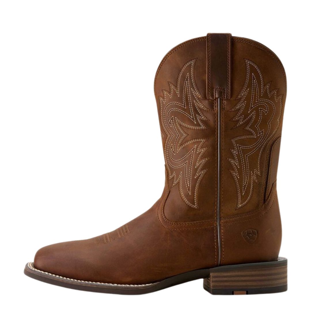 La WESTERN BIG RIG W-SQUARE COWBOY BOOT se compose de cuir marron, de surpiqûres décoratives, d'un bout carré, de tirettes, d'un talon bas empilé, d'une semelle visible et d'une broderie détaillée sur la tige.