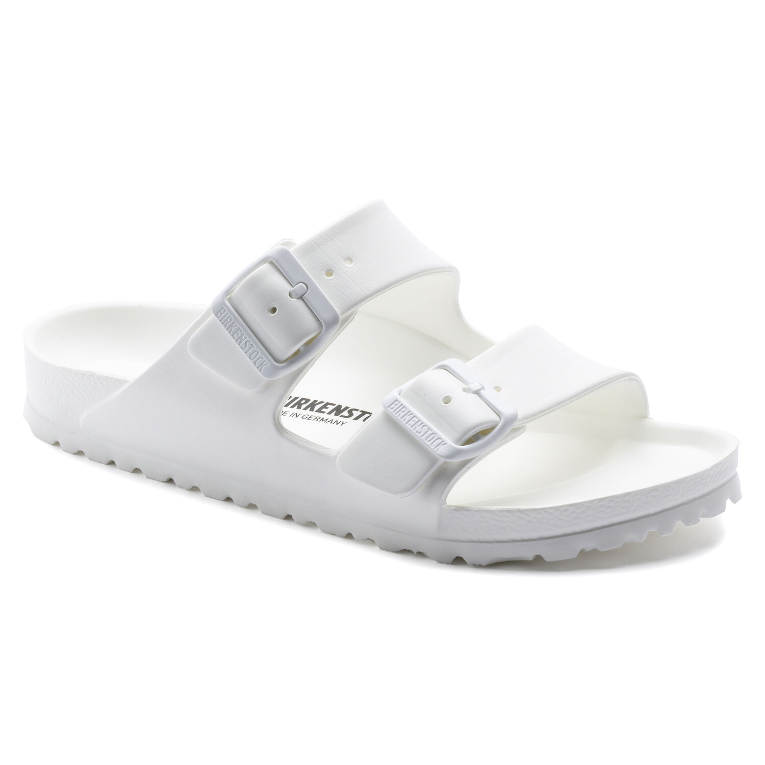 Une paire de sandales Birkenstock Arizona Essentials Étroite couleur blanche sur un fond blanc. Les sandales ont une assise anatomique et une semelle extérieure en EVA souple. Les sandales ont deux boucles métalliques pour un ajustement sûr.