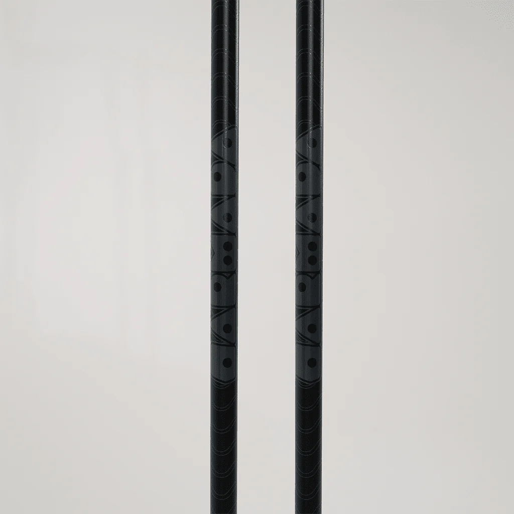 Deux objets cylindriques noirs aux motifs texturés sont positionnés verticalement sur un fond clair uni. Les surfaces des objets présentent des motifs géométriques avec des points et des rectangles.
