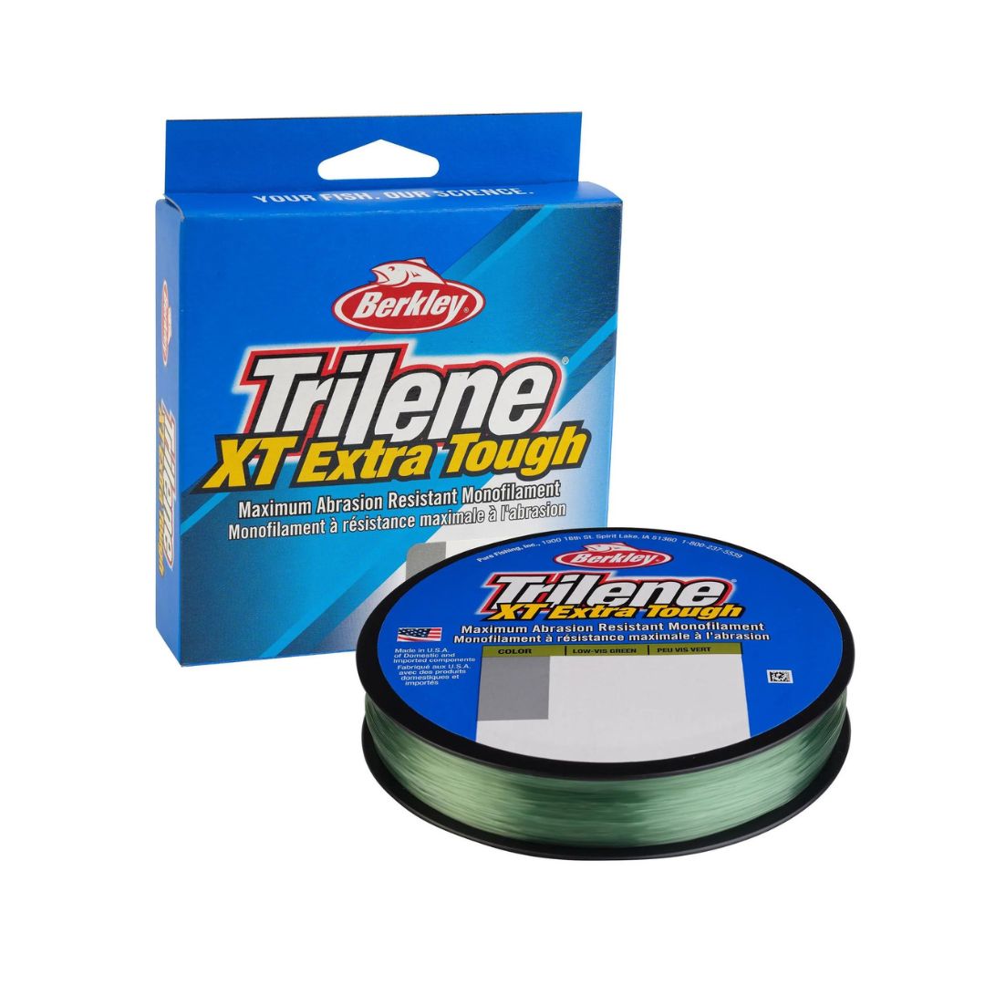 Une bobine de fil de pêche Berkley Trilene XT Extra Tough est présentée devant son emballage bleu, qui affiche le nom du produit et souligne sa résistance maximale à l'abrasion.