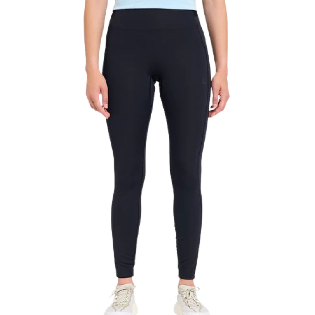 Une personne portant un legging noir W FST TIGHT 29", un haut bleu clair et des baskets blanches se tient debout sur un fond blanc uni. L'image montre son corps des épaules aux pieds.