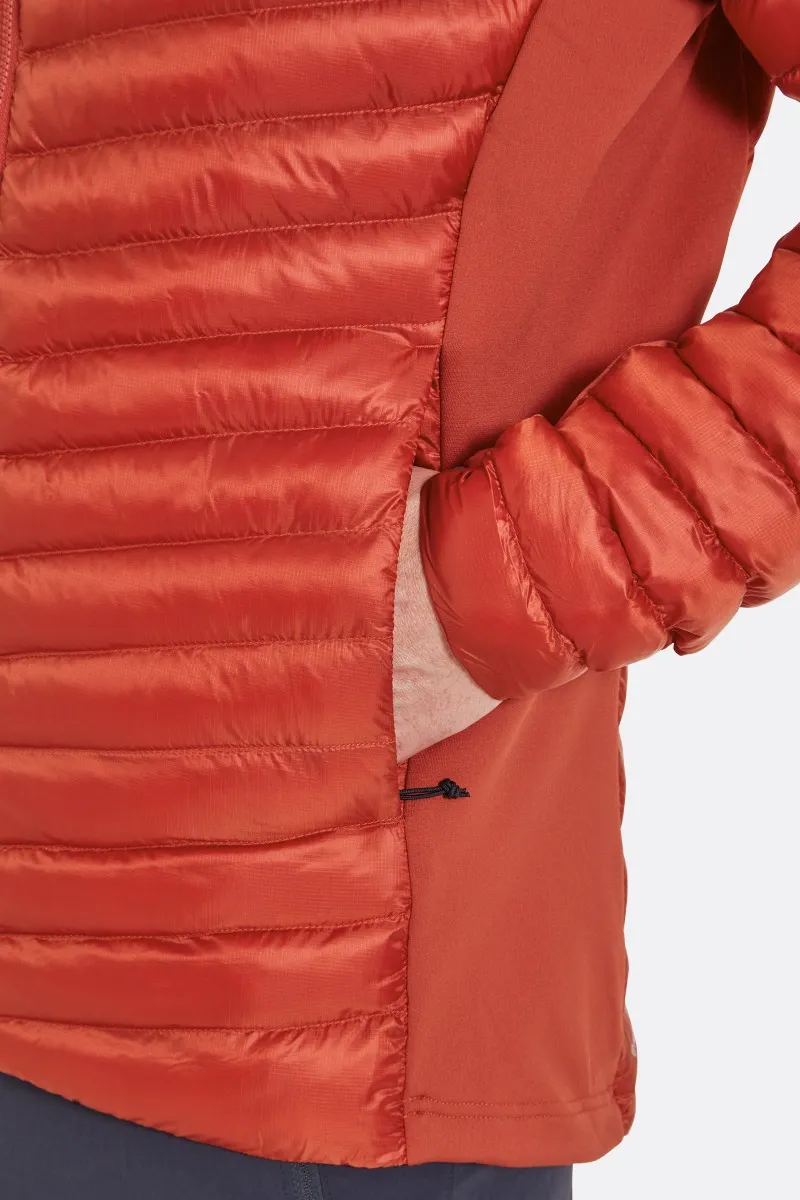 Gros plan d'une personne portant une veste matelassée de couleur rouille. La veste présente des coutures horizontales et une poche zippée où la personne pose sa main. Le tissu a une texture brillante et le fond est blanc uni.