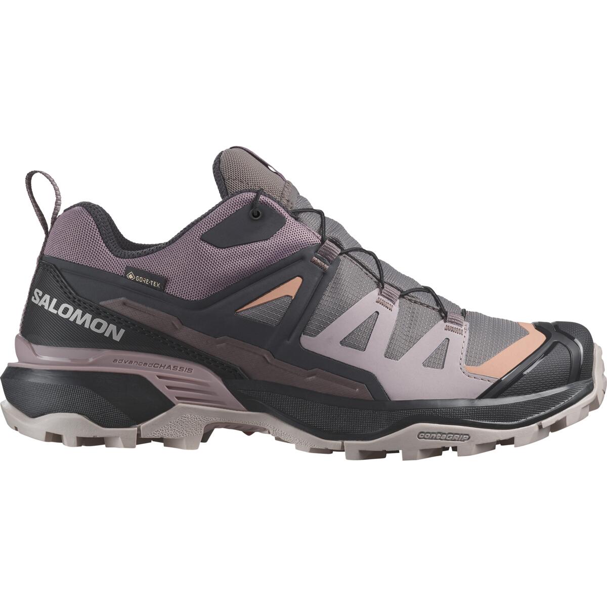 Une chaussure de trail running grise et rose avec une semelle robuste et une conception durable et imperméable. La chaussure est dotée de superpositions pour le maintien et du nom de la marque « Salomon » affiché sur le côté.