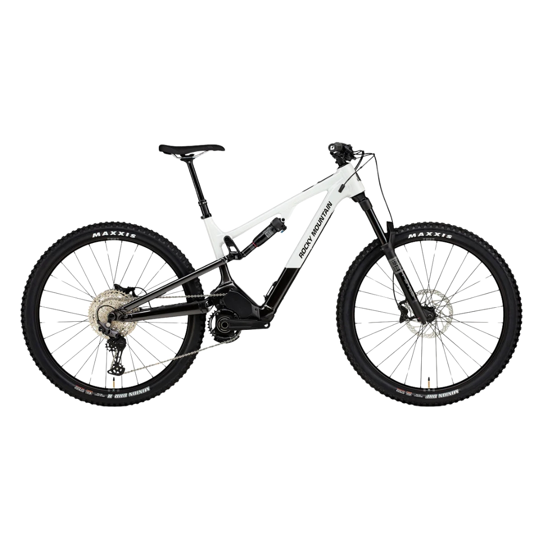 Un VTT électrique blanc et noir avec des pneus épais et un cadre robuste. Le vélo est équipé de freins à disque et d'une transmission Shimano. Le nom de la marque est visible sur le cadre. Le fond est blanc uni.