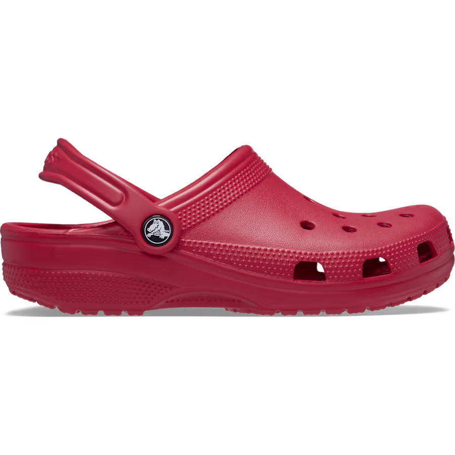 Une sandale CROCS CLASSIQUE UNISEXE de couleur rouge, dotée d'orifices d'aération, d'une semelle texturée et d'une bride pivotante au talon, présentée de profil sur un fond blanc.