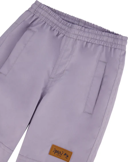 Un pantalon violet clair avec une taille élastique et deux poches latérales. Un petit patch marron avec un logo est cousu sur le bas de la jambe droite. Le pantalon est soigneusement agencé sur un fond uni.