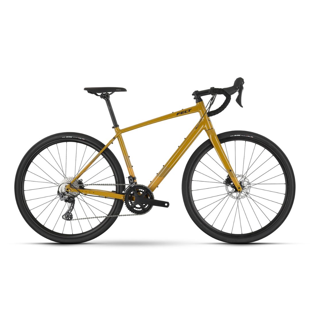 Un vélo gravel jaune avec guidon, selle et pneus noirs est présenté de profil sur fond blanc. Il est équipé de freins à disque et d'un guidon de course.