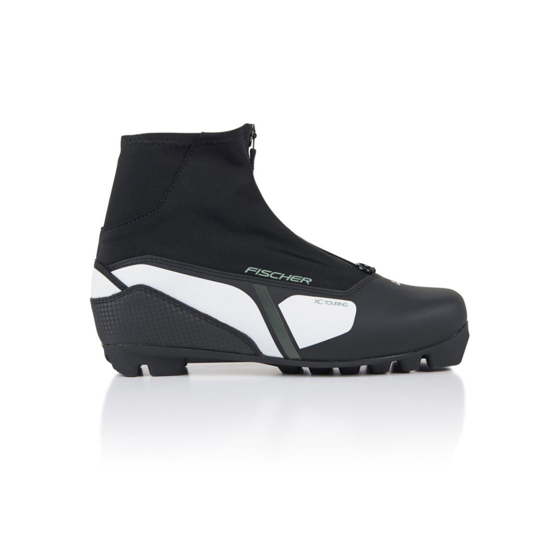 La BOTTE DE SKI DE FOND FISCHER XC TOURING WS POUR FEMME est une chaussure de ski de fond pour femme, noire et blanche, avec un design à hauteur de cheville, un lacet zippé et une semelle robuste, présentée de côté sur fond blanc.