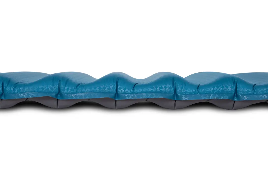 Vue latérale rapprochée d'un matelas de couchage gonflable bleu et gris avec une surface ondulée et profilée.