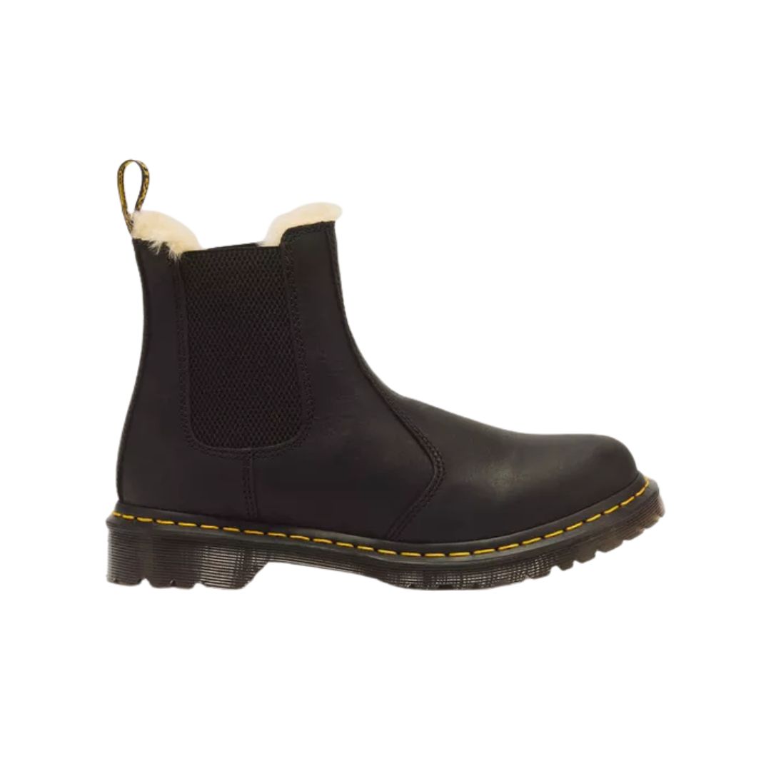 Le modèle 2976 LEONORE est une botte Chelsea en cuir noir dotée de panneaux latéraux élastiques, d'une languette, d'une semelle aux coutures jaunes et d'une doublure en polaire blanche apparente.