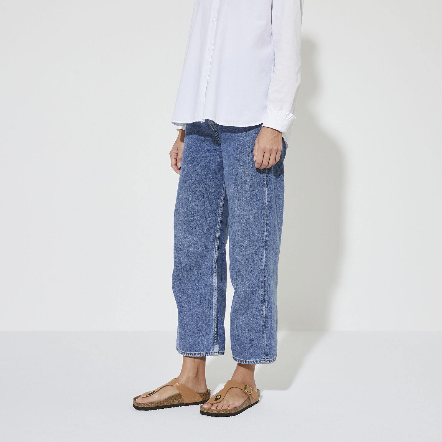 Une paire de sandales Birkenstock Gizeh Vegan Birkibuc noires sur un fond blanc. Les sandales ont une assise anatomique en liège et une semelle extérieure en EVA souple. La sangle unique est fabriquée en cuir synthétique Birkibuc, qui est doux et résistant à l'eau. Les sandales ont un design minimaliste et élégant.