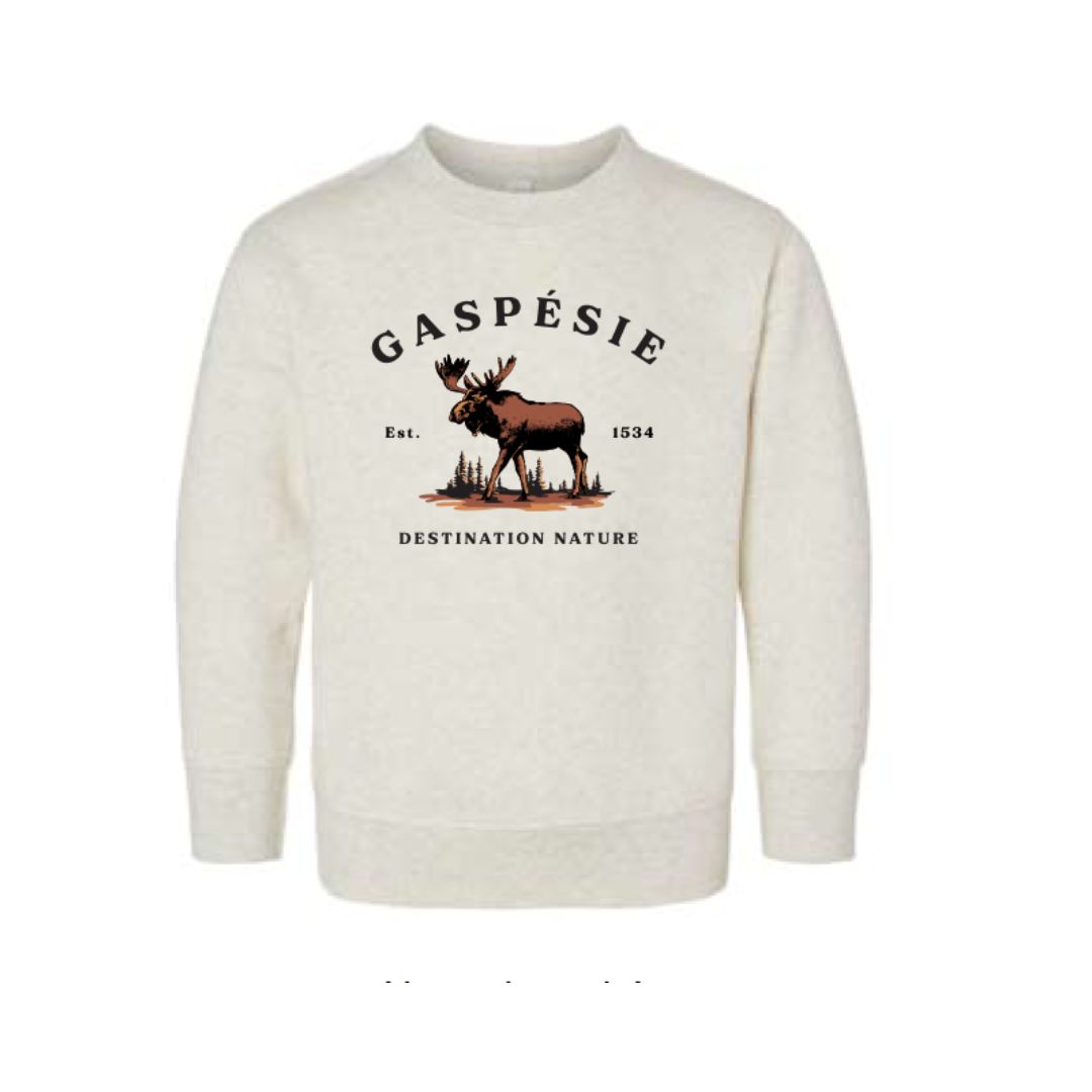 Un chandail à col ras du cou de couleur crème arborant le logo " Gaspésie Je T'aime Logo Orignal 2.0 " avec un orignal sur de l'herbe, " Gaspésie Est. 1534 " au-dessus, et " Destination Nature " en dessous. Modèle unisexe à manches longues pour bébé.
