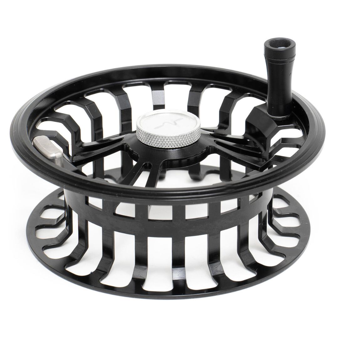 Un gros plan de la BOBINE GUIDELINE HALO BLACK STEALTH SPOOL #79 DH, avec un cadre ouvert noir, un bouton central argenté, et une petite attache cylindrique sur le bord.