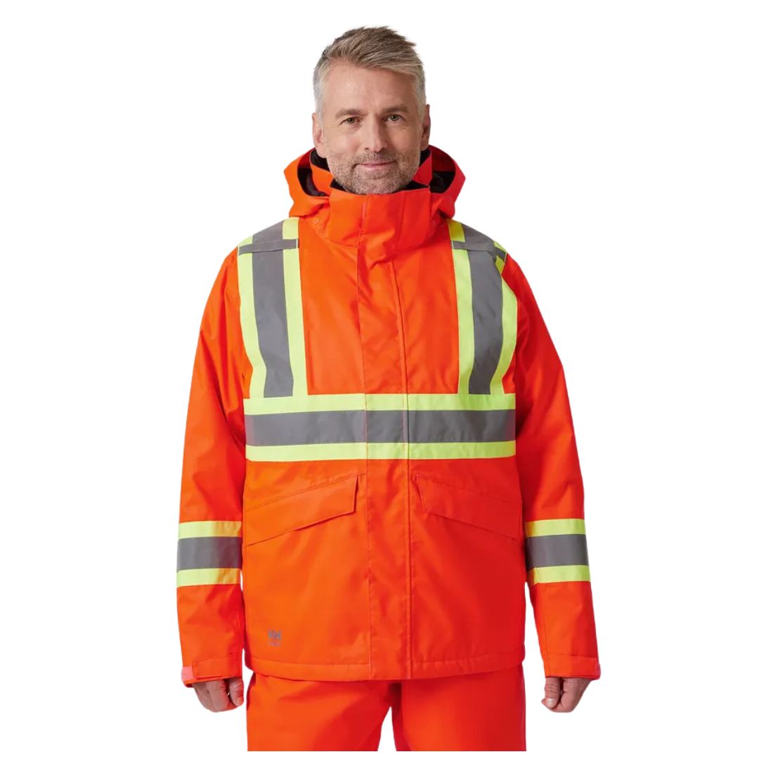 Un homme portant une veste d'hiver ALTA WINTER JACKET CSA, une veste d'hiver orange haute visibilité dotée de bandes réfléchissantes argentées et d'une capuche.