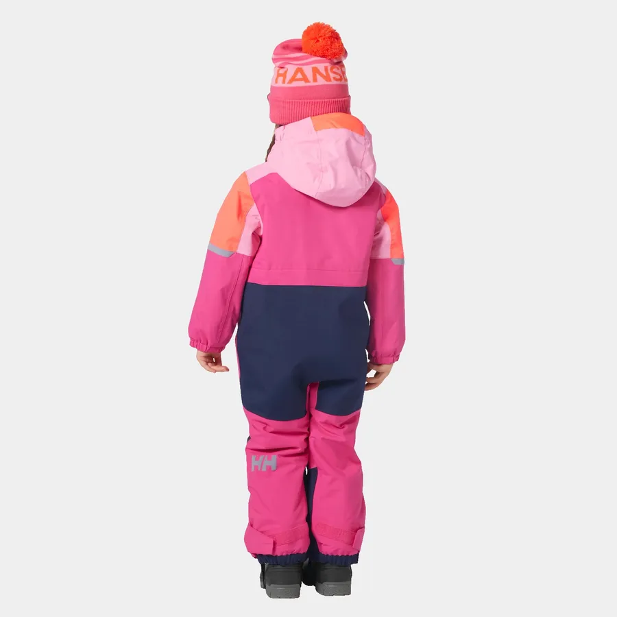 Un enfant porte une combinaison de neige aux couleurs vives et contrastées, dos à la caméra. La combinaison est une combinaison de rose, de violet et d'orange. L'enfant porte un bonnet en tricot assorti avec un pompon sur le dessus et des bottes de neige noires. L'arrière-plan est blanc uni.