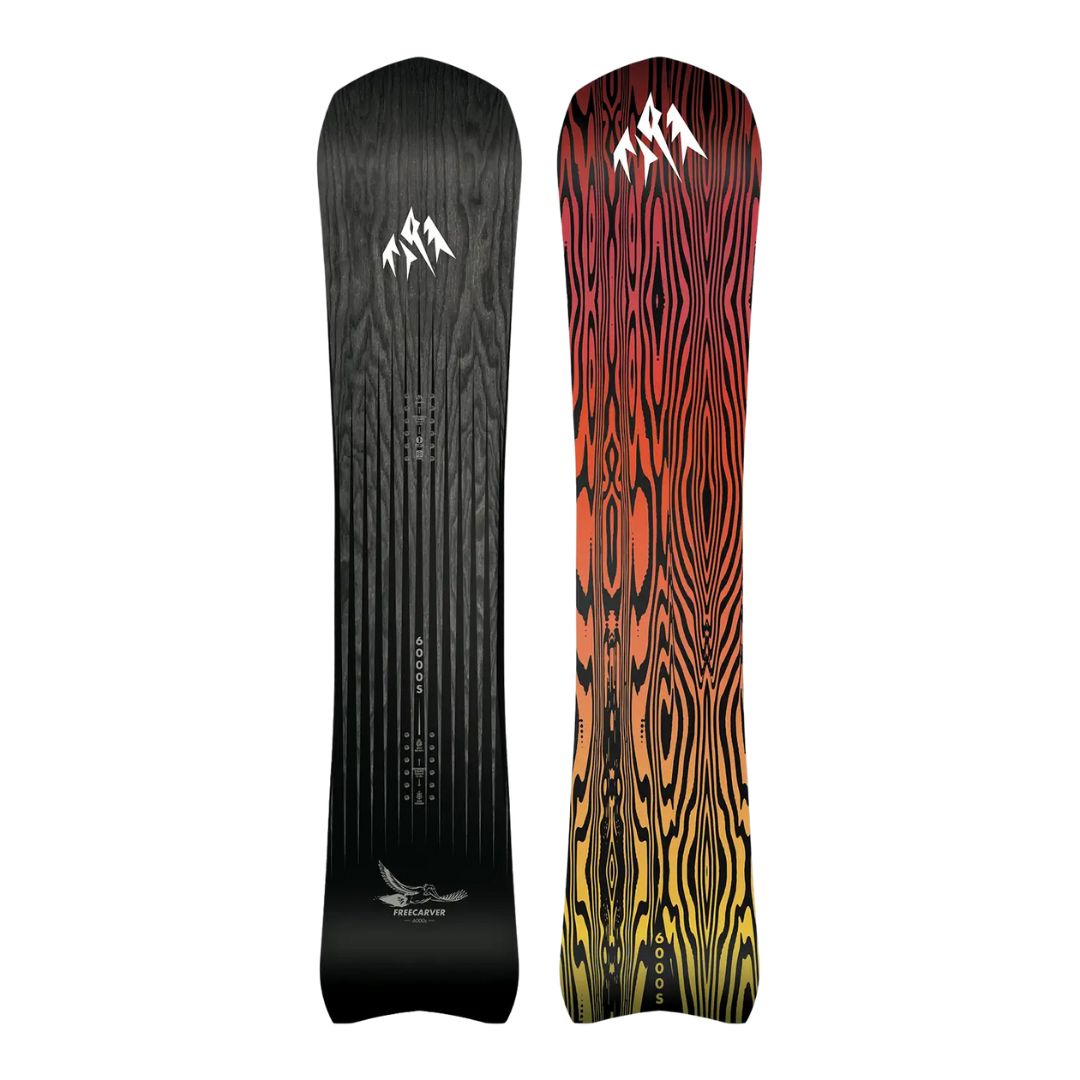 Deux snowboards PLANCHE À NEIGE JONES FREECARVER 6000S se tiennent debout. L'avant est noir avec une texture de grain de bois, des logos blancs et un graphique d'oiseau ; l'arrière affiche un grain de bois audacieux et ondulé en rouge, orange et jaune.