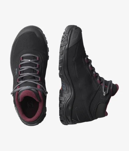 Une paire de chaussures de randonnée noires avec des lacets gris et un intérieur marron. Une des chaussures est présentée de dessus et l'autre de côté, mettant en valeur la semelle robuste et le soutien de la cheville.