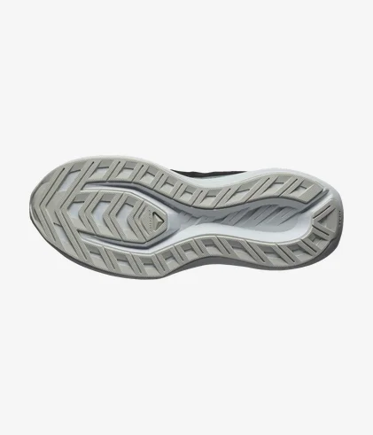 L'image montre la semelle d'une chaussure avec un motif de lignes en zigzag et de rainures texturées. La semelle est principalement grise avec une teinte plus claire sur les bords.