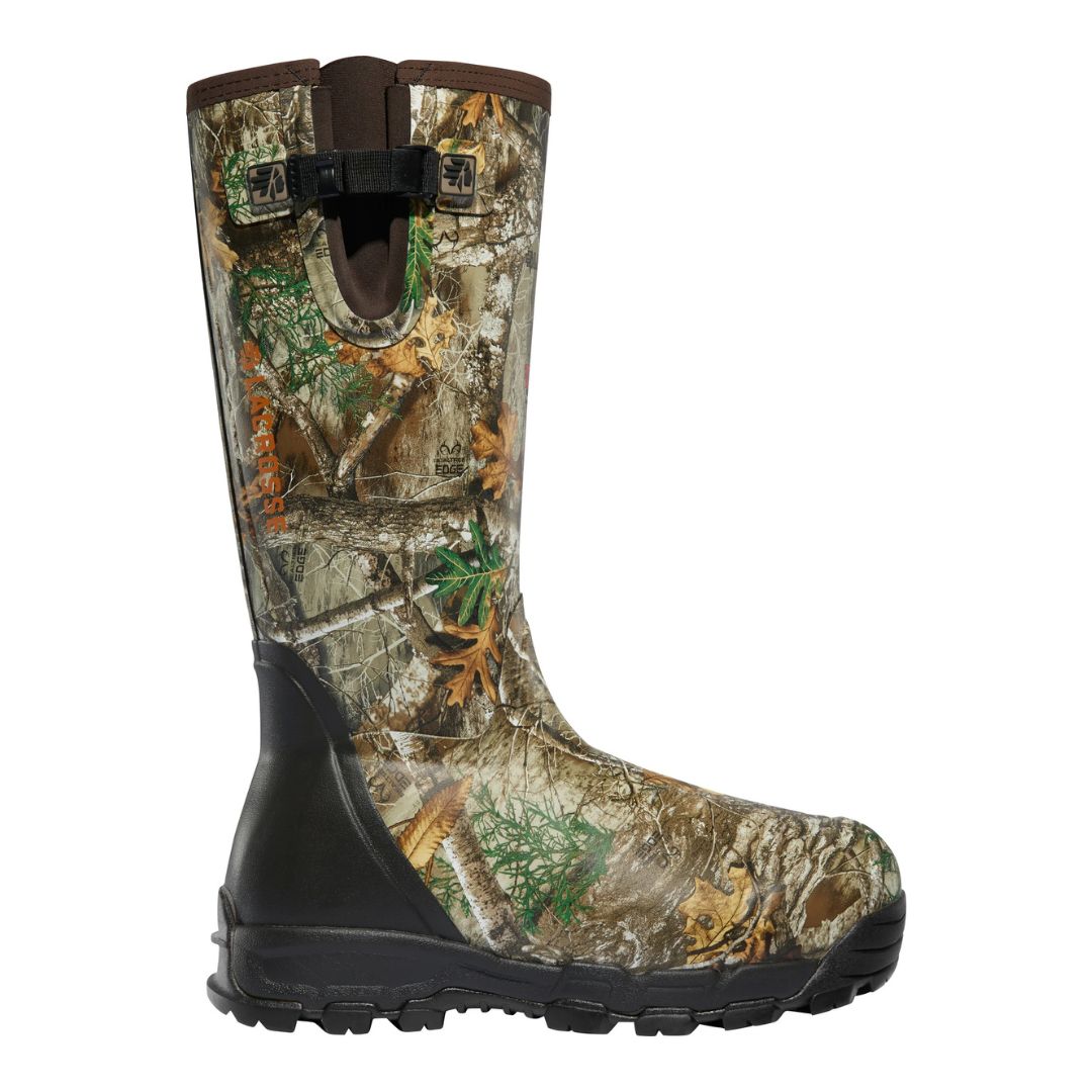 L'ALPHABURLY PRO SIDE ZIP 18" 1000G est une botte de chasse à hauteur de genou avec une semelle noire robuste et un motif camo marron-vert avec des feuilles, conçue pour les activités de plein air.