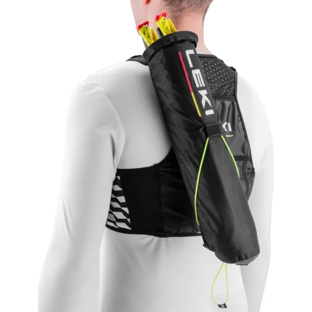 Une personne portant un carquois de sport noir avec des bâtons de trekking jaunes, portant le logo de la marque LEKI, par-dessus une chemise blanche à manches longues. Le carquois est fixé dans le dos et sur l'épaule.