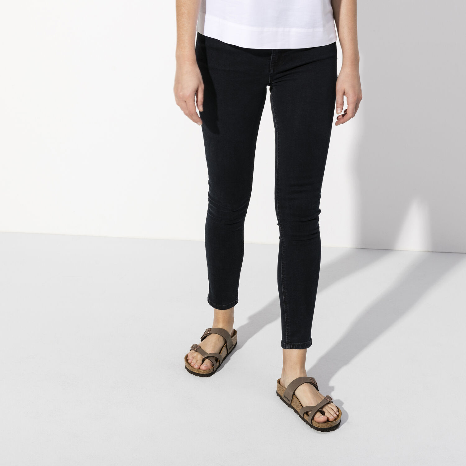 Une paire de sandales Birkenstock Mayari Birkibuc de couleur "Mocha" sur un fond blanc. Les sandales ont deux brides réglables avec des boucles en métal. Les brides sont fabriquées en Birkibuc, un matériau synthétique ressemblant au cuir, doux, durable et facile à nettoyer. Le lit de pied est anatomique en liège et possède une doublure en suède. La semelle extérieure est en EVA, un matériau léger et absorbant les chocs.