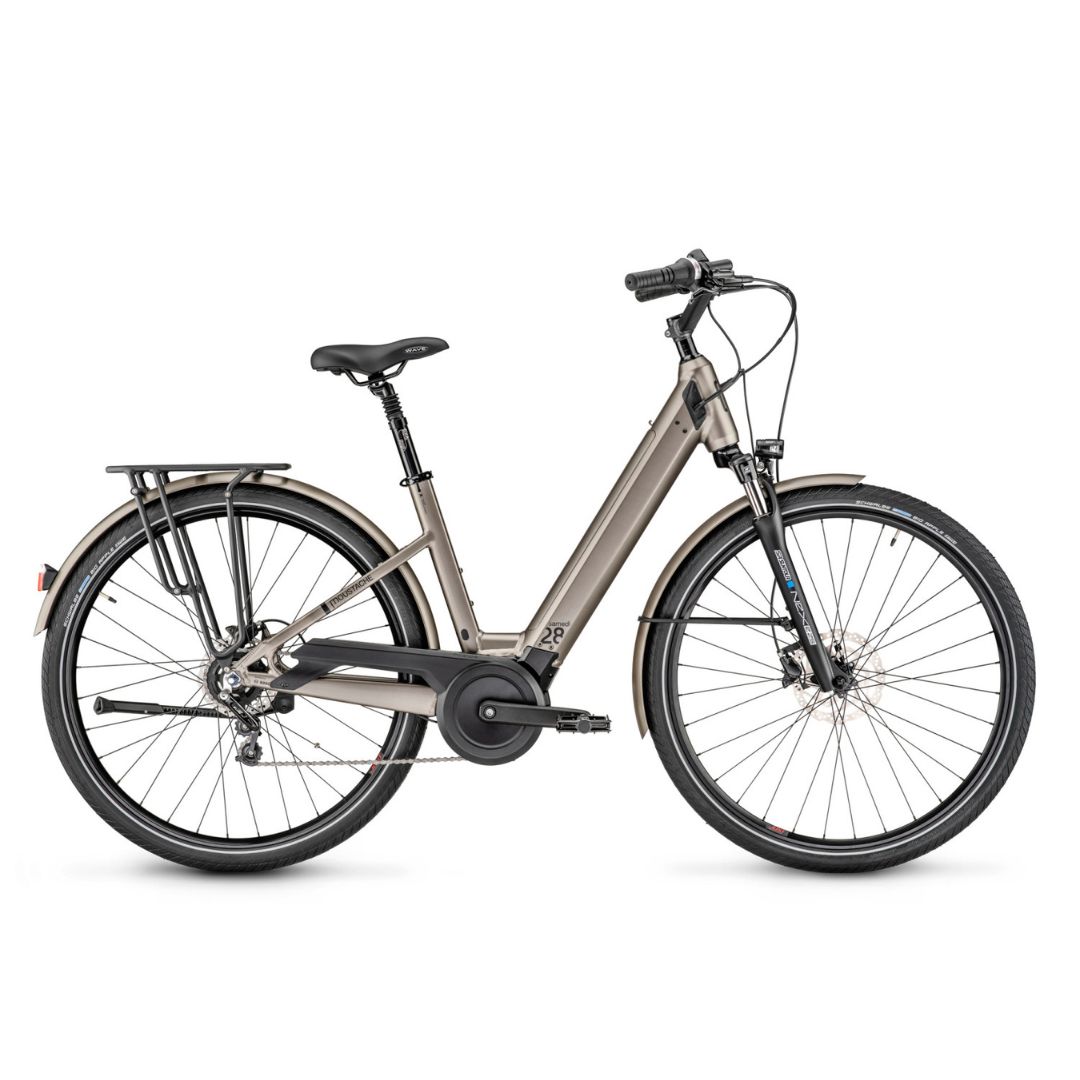 Un vélo électrique moderne et argenté avec un cadre traversant, une suspension avant, un porte-bagages arrière et des garde-boue, présenté de profil sur fond blanc.