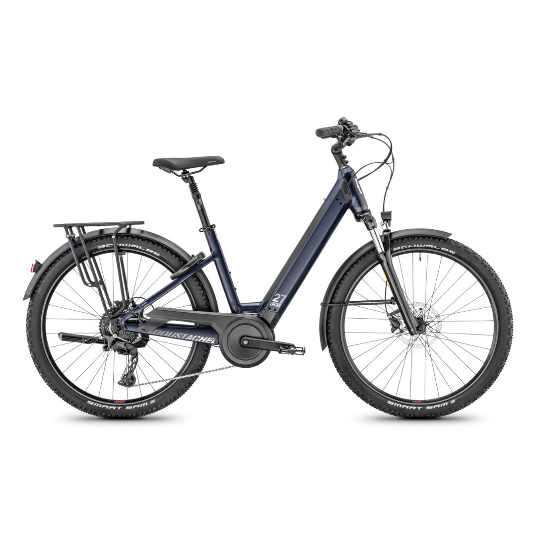 Un vélo électrique bleu foncé avec cadre ouvert, suspension avant, porte-bagages arrière, garde-boue et pneus épais. Il est équipé de freins à disque et d'une batterie intégrée au cadre.